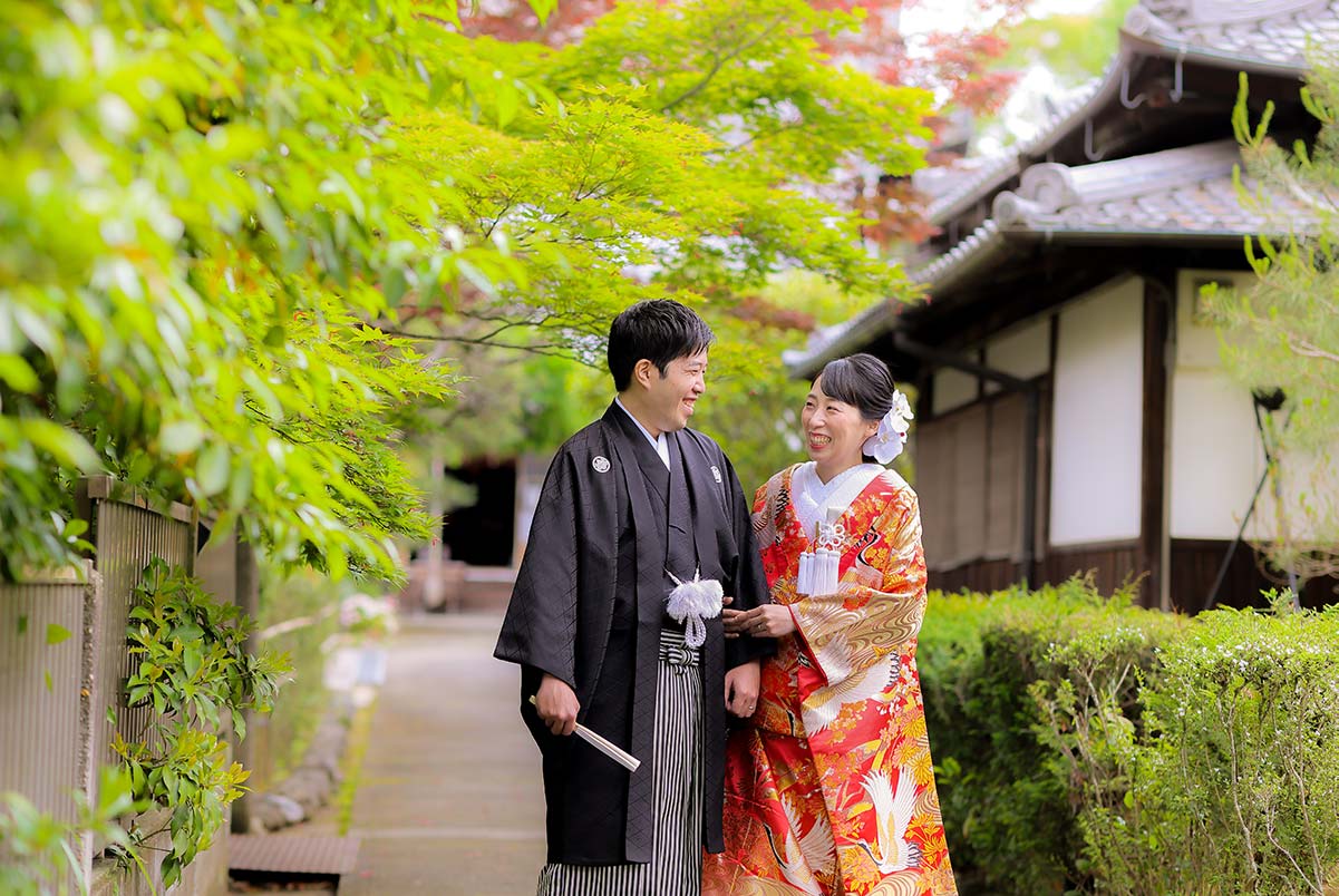 京都のお寺の境内で新緑を背景に手を取り合う新郎新婦様
