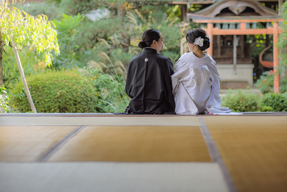 白無垢姿でお庭を背景に腰掛けた新郎新婦様
