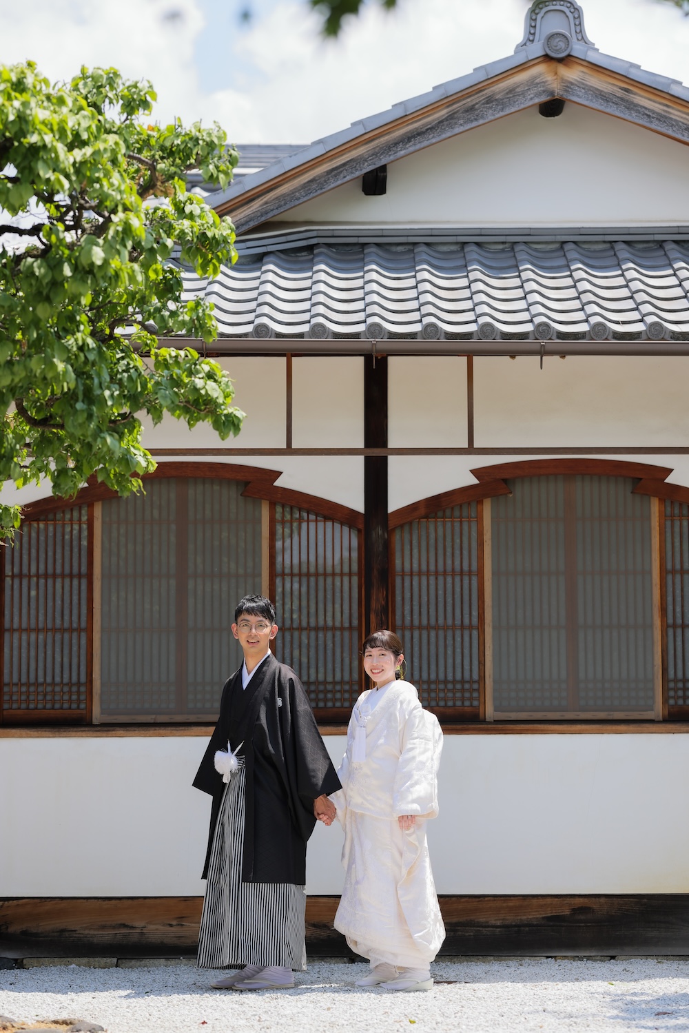 白壁を背景に歩いている新郎新婦様。