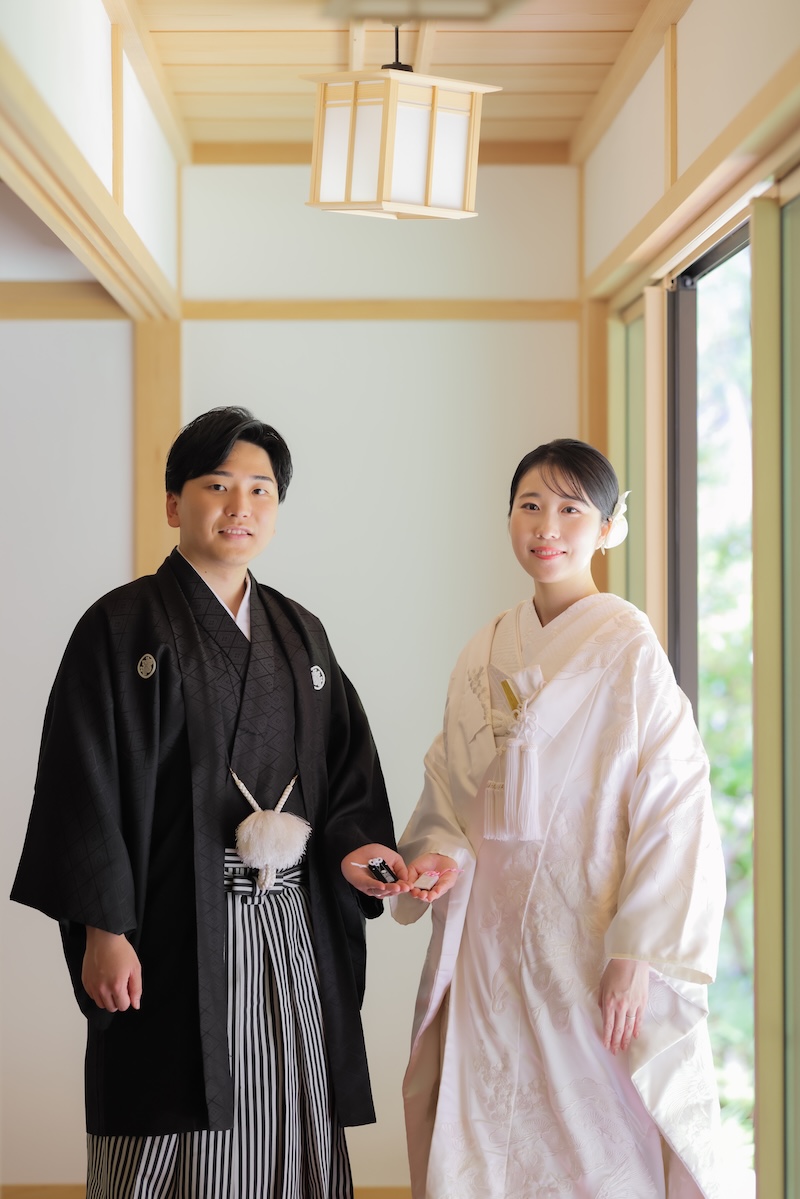 夫婦守りを持った白無垢姿・羽織袴の新郎新婦様