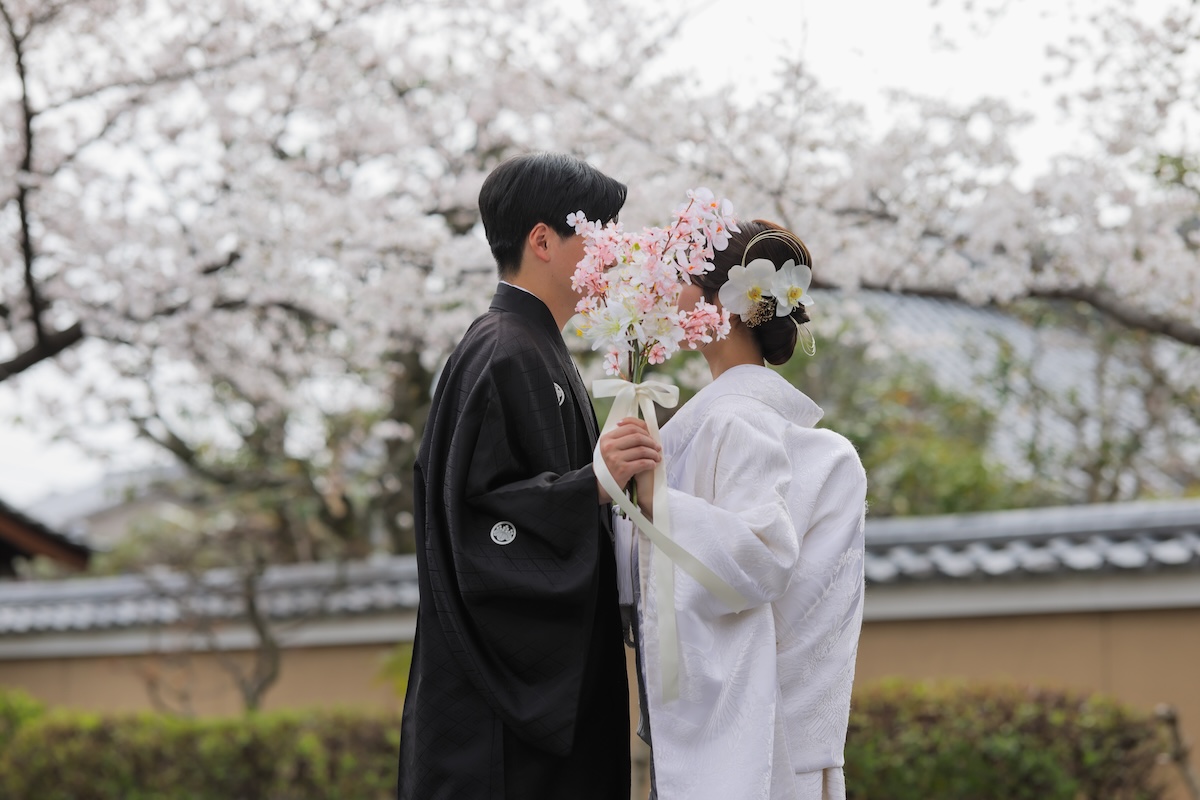桜を背景にブーケで口元を隠したお写真イメージ