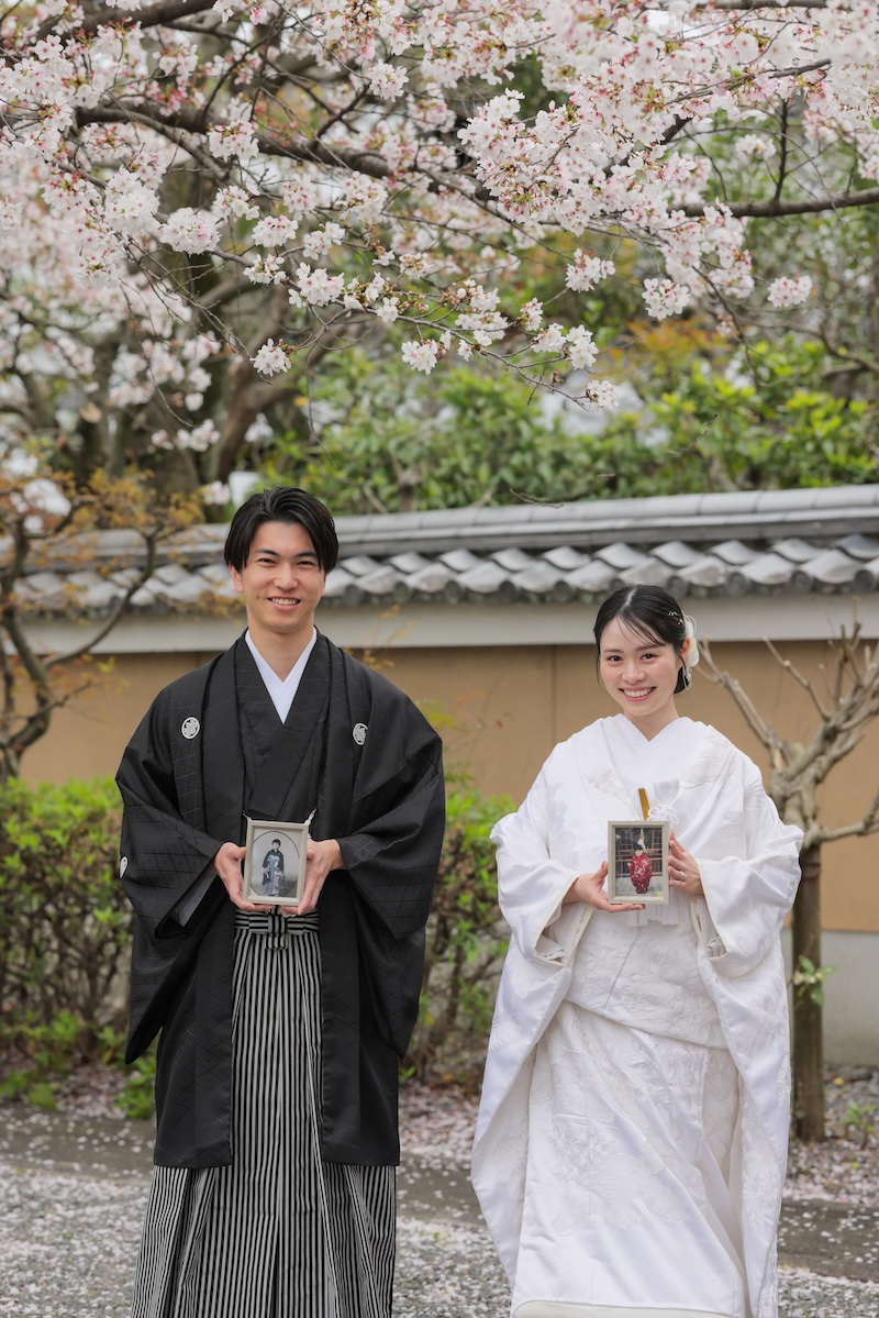 桜と幼い頃のお写真を持った和装姿の新郎新婦様