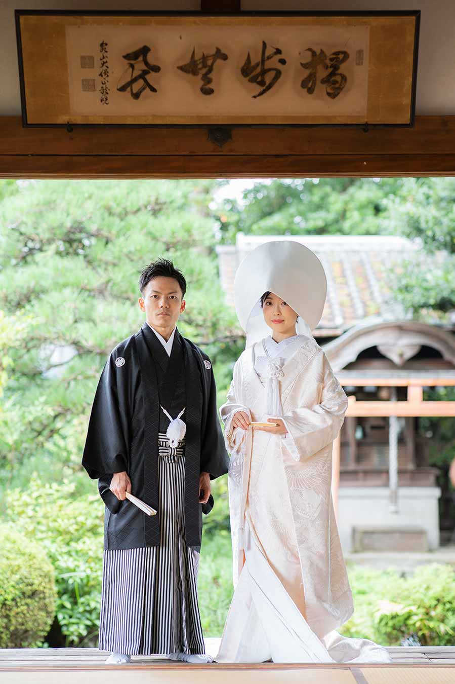 お庭をバックに立ち姿の白無垢と羽織袴の新郎新婦様