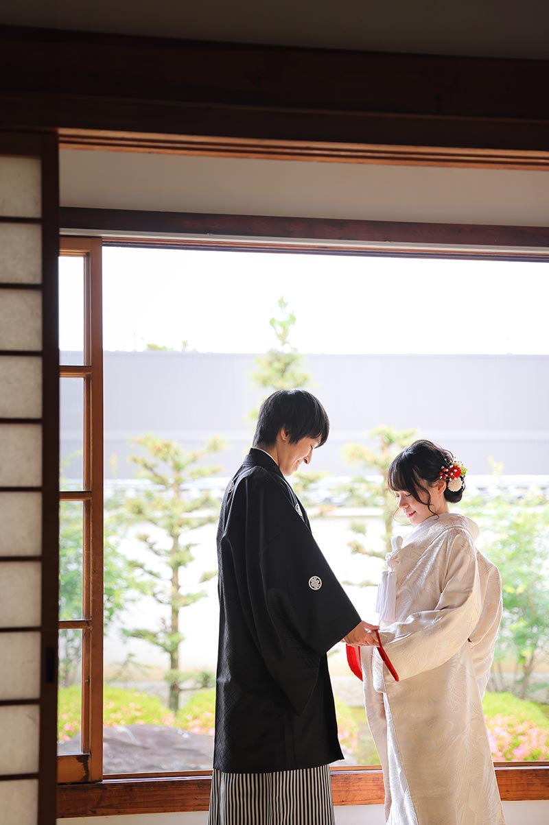 お庭を背景に手を取り合う和装前撮り写真